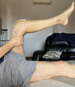 Paciente realizando uma mobilização em flexão de joelho, utilizando da força de gravidade.
